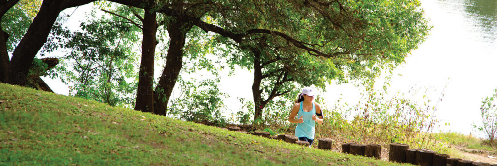 A woman running on the hike & bike trail along Lady Bird Lake in downtown Austin Texas