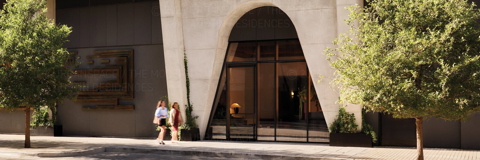 Two women stroll by the front entrance of The Modern Austin Residences