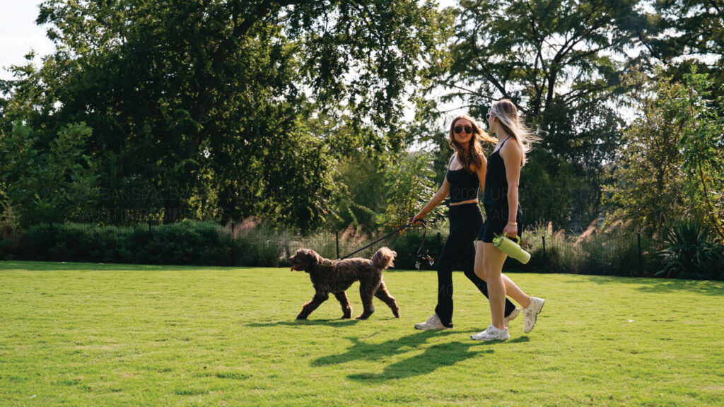 Two women walking a dog in the Rainey Street Trailhead Park near The Modern
