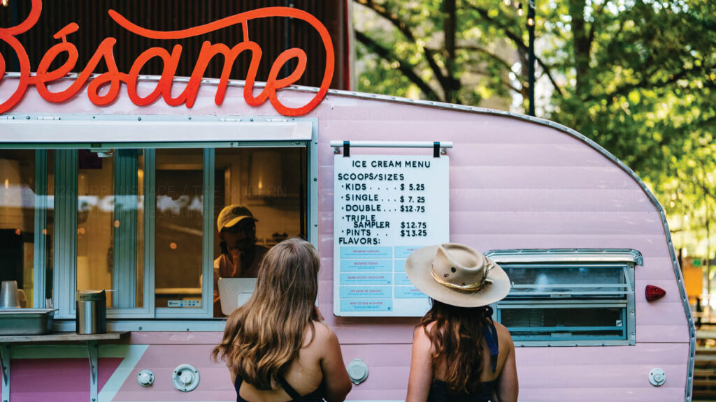 Two women peruse the menu at the Besame ice cream truck near The Modern on Rainey Street