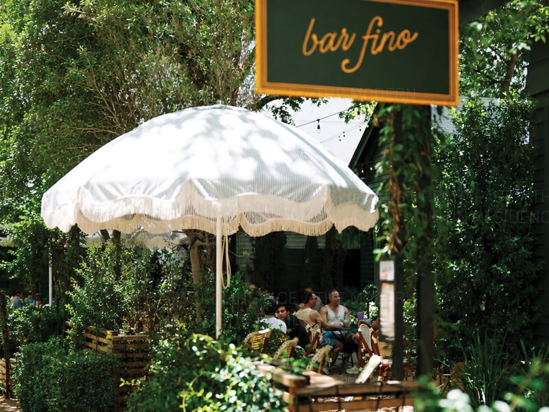 Bar Fino sign with umbrella shade and people at the bar on Rainey Street